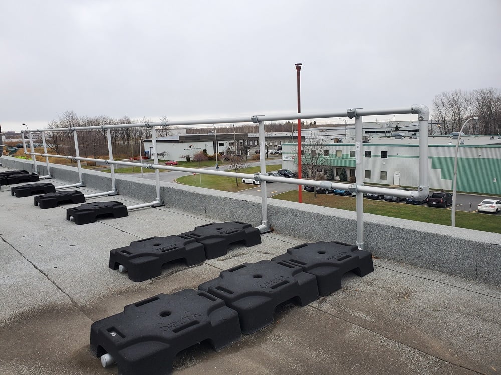 freestanding guardrails on a flat rooftop with parapet. VSS Classic configuration with rubber counterweights and aluminum tubing.